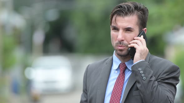 Young Happy Hispanic Businessman Talking on the Phone Outdoors