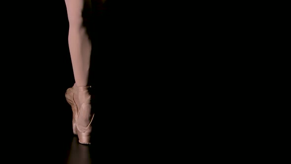 Graceful Legs of a Ballerina in White Pointe Shoes. Ballerina Shows Classic Ballet Pas. Shot in a