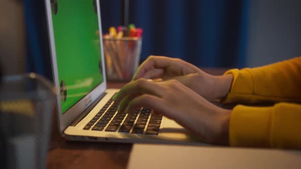 Beautiful Black Woman Sitting at Her Desk Works on a Laptop with Green Chroma Key Mockup Screen