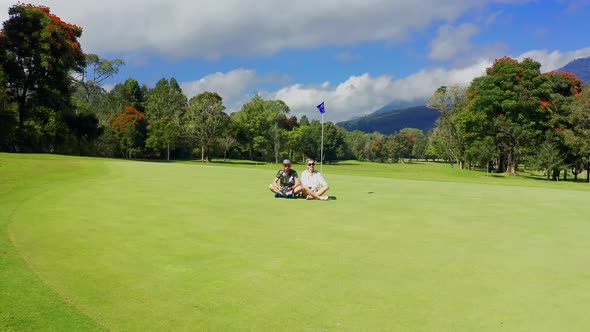 Young Couple Sitting on a Golf Course in Mountains at the Bali, Indonesia. Aerial View 