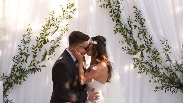 Groom and Bride in Dress Kiss Hugging Each Other