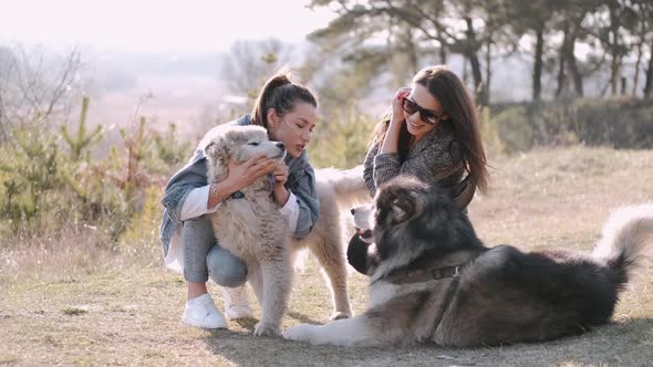 Young Beautiful Women Are Smiling and Hugging with Their Fluffy Cute Dogs