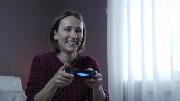 Excited girl playing video game and using joystick. Smiling woman playing online video games