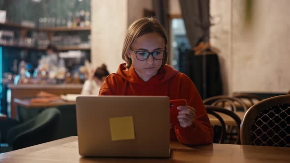 Young Caucasian Woman Freelancer or Blogger Working on Laptop in Cafe