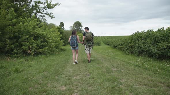 Lovely Couple with Rucksacks Walks in Embraces on Nature