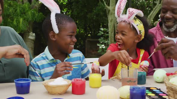 Animation of happy diverse grandmother and grandchildren painting easter eggs in garden