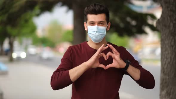 Happy doctor in protective mask on face gesturing heart symbol by hands.