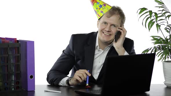 Drank Young Businessman in Festive Cap Blowing a Whistle and Speak on Phone