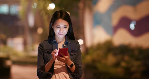 Young woman check on mobile phone in city at night