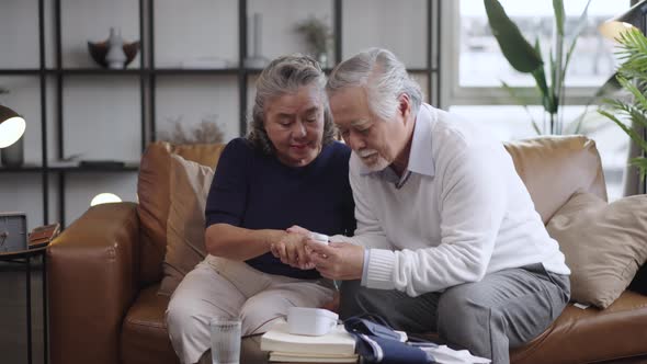 Asian elderly couple using oxygen pulse fingertip for test oxygen to the wife in the house