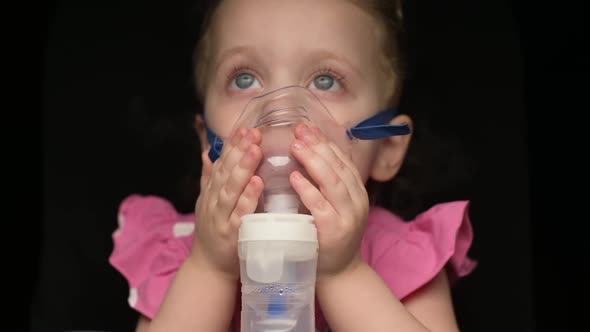 A little girl lies on the lungs and airways with inhalation on a dark background