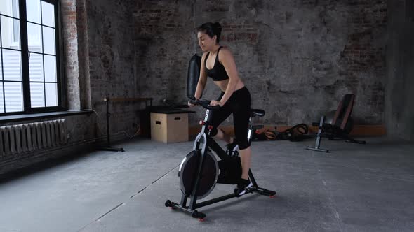 Portrait adult Indian woman training on static bike at cycling class. Fitness woman spinning bike