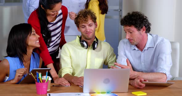 Group of business executives interacting over laptop