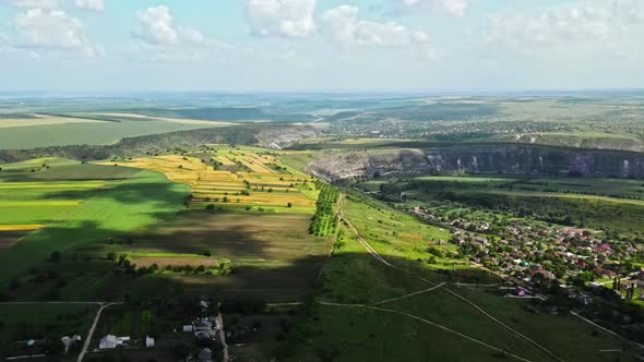 Aerial drone view of nature, valley with river and village, hills and fields, greenery, Moldova