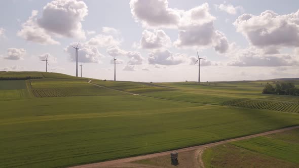 Wind park in the fields of Rhineland palatinate, Germany underneath a bright blue sky with soft cumu
