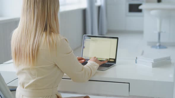 Young girl working at a laptop at home office. Young woman typing on laptop at the desk