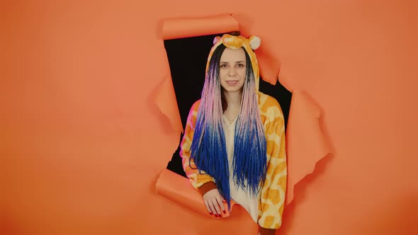 Young Woman in Pajamas of Giraffe in Hole of Orange Background