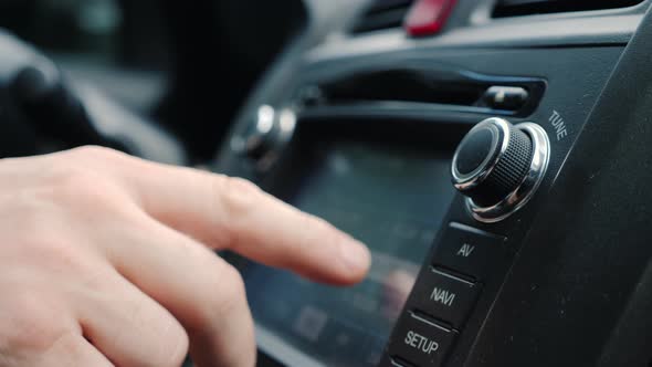 Male Hand Tunes the Radio in the Car