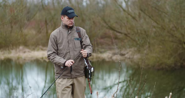 Confident Man Preparing Fishing Rod at Lakeshore