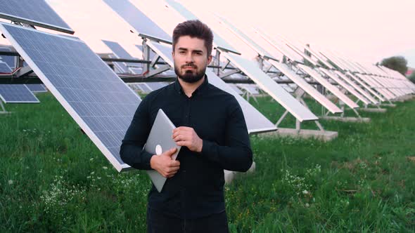 The Portrait of a Cheerful Chief Engineer on the Background of the Solar Panel.