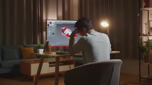 Asian Male Footwear Designer Having A Headache While Designing Shoe On A Desktop At Home