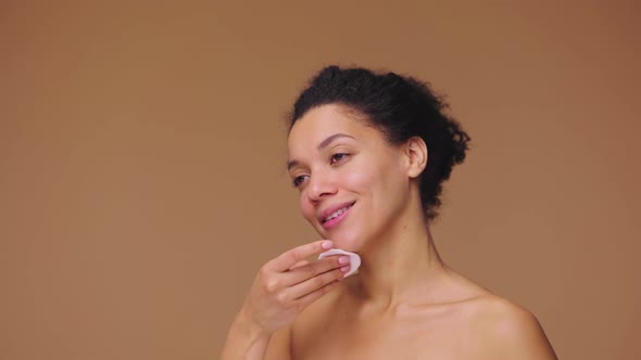 Beauty Portrait of Young African American Woman Cleansing Face with White Cotton Pad Removing Makeup