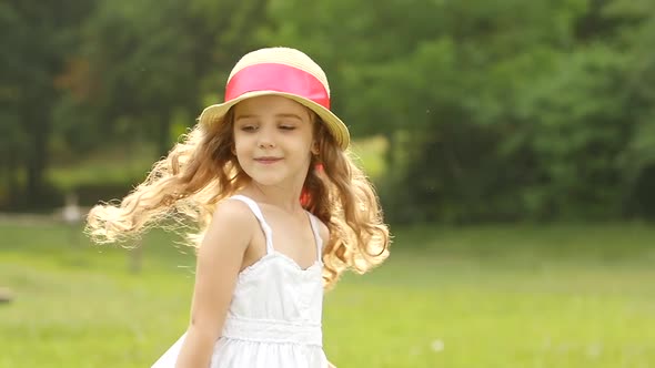 Little Girl Walks in the Park and Turns Around in a Circle. Slow Motion