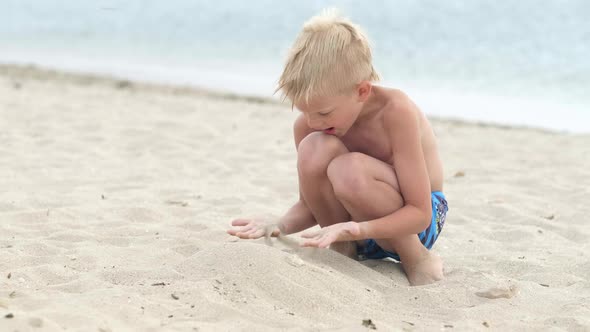 Little Blonde Boy Playing with Sand on Beach Ocean Sea