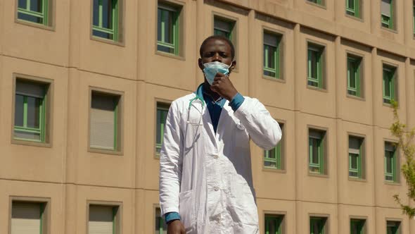 confident black doctor pulling down his mask and smiling at the camera