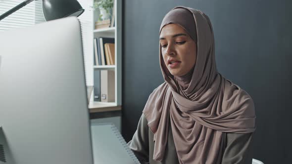 Muslim Woman Discussing Documents on Online Call on Computer