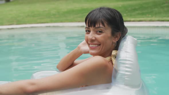 Happy caucasian woman wearing swimming suit with inflatable at swimming pool