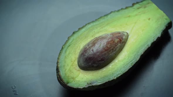 Half of an Avocado with a Stone Rotates in a Circle on a Black Background