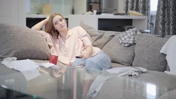 Wide Shot Portrait of Bored Lonely Beautiful Woman Watching TV in Living Room Switching Channels