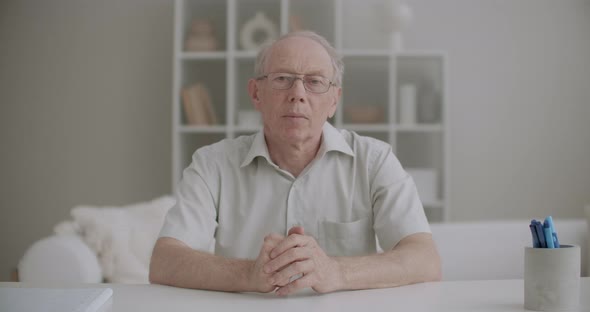 Retiree Man Is Greeting and Talking Distantly By Online Chat, Medium Portrait at Living Room