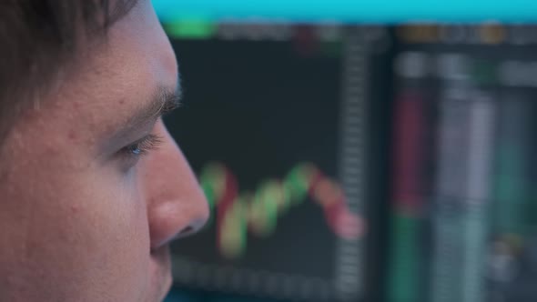 close-up face of a young businessman looking to the trading schedule on the monitors.