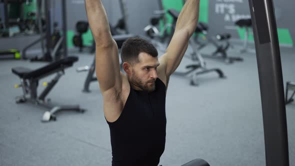 Male Training Back and Hands Muscles Doing Pulls Weight Exercise in a Gym