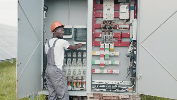 African American Man in Grey Overalls and Orange Helmet Repairing Cables in