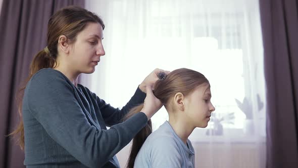 Charming Little Girl is Smiling While Her Beautiful Young Pregnant Mother is Combing Daughter's Hair