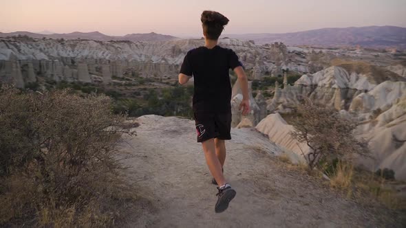 Young man runs towards a scenic viewpoint at sunset