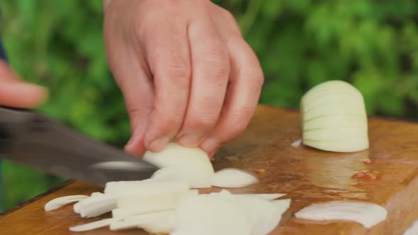 Male Hands Slicing Fresh White Onion on A Cutting Board