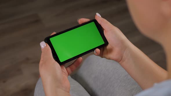 Closeup of a Young Woman Holding a Smartphone with a Green Screen