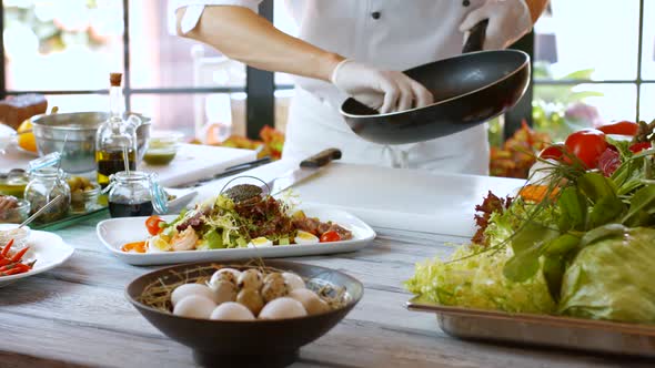 Hand Puts Potatoes on Salad.