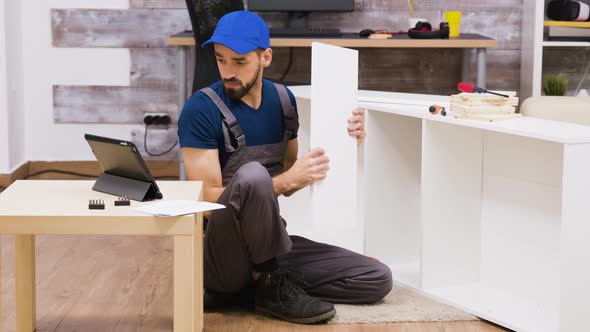 Male Worker in Overalls with a Cap Assembly a Shelf