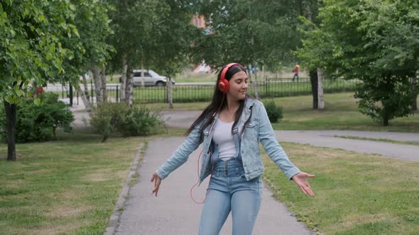 Funny Cheerful Girl Dancing in the Park Listening To Music on Headphones. Fun Mood