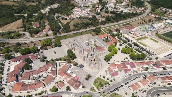 Cityscape of Batalha and majestic monastery complex building, aerial descend flying toward view