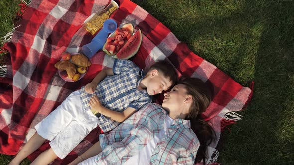 Mother and Happy Little Son Speak and Laugh Lying on Grass