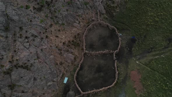 Aerial top view over a small hut surrounded by stone boundary walls beside inca terrace farms in Bol