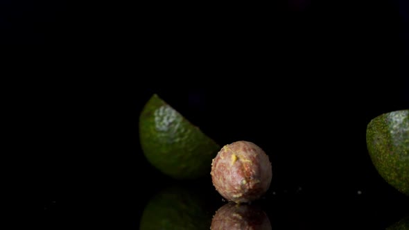 One Ripe Cut Green Avocado Falling on a Table in Slow Motion on a Dark Background.