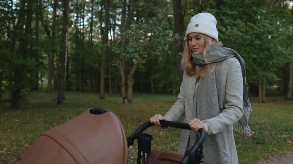 young woman walks with a stroller in the park