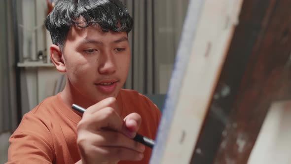 Asian Artist Boy Holding Paintbrush And Mixing It With Colour Before Painting On The Canvas